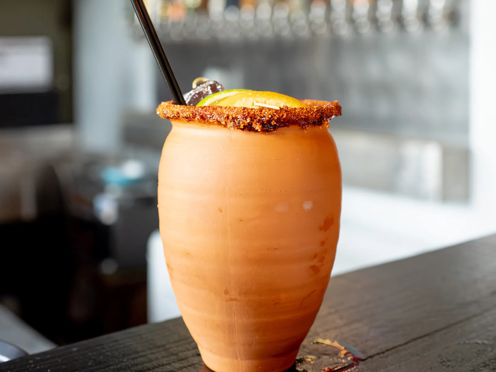 A Cantarito in a clay cup with a chili-salt rim on the bar