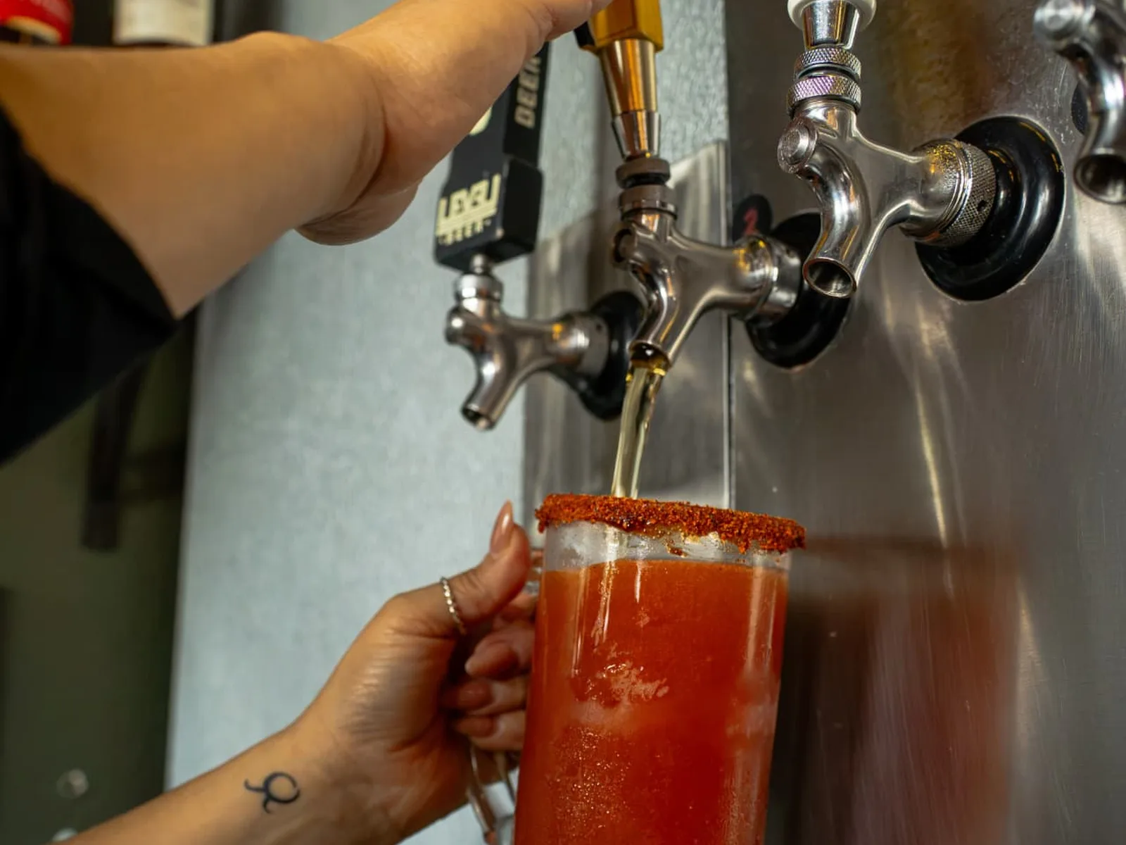 A frosty mug with a chili-salt rim being filled from the tap